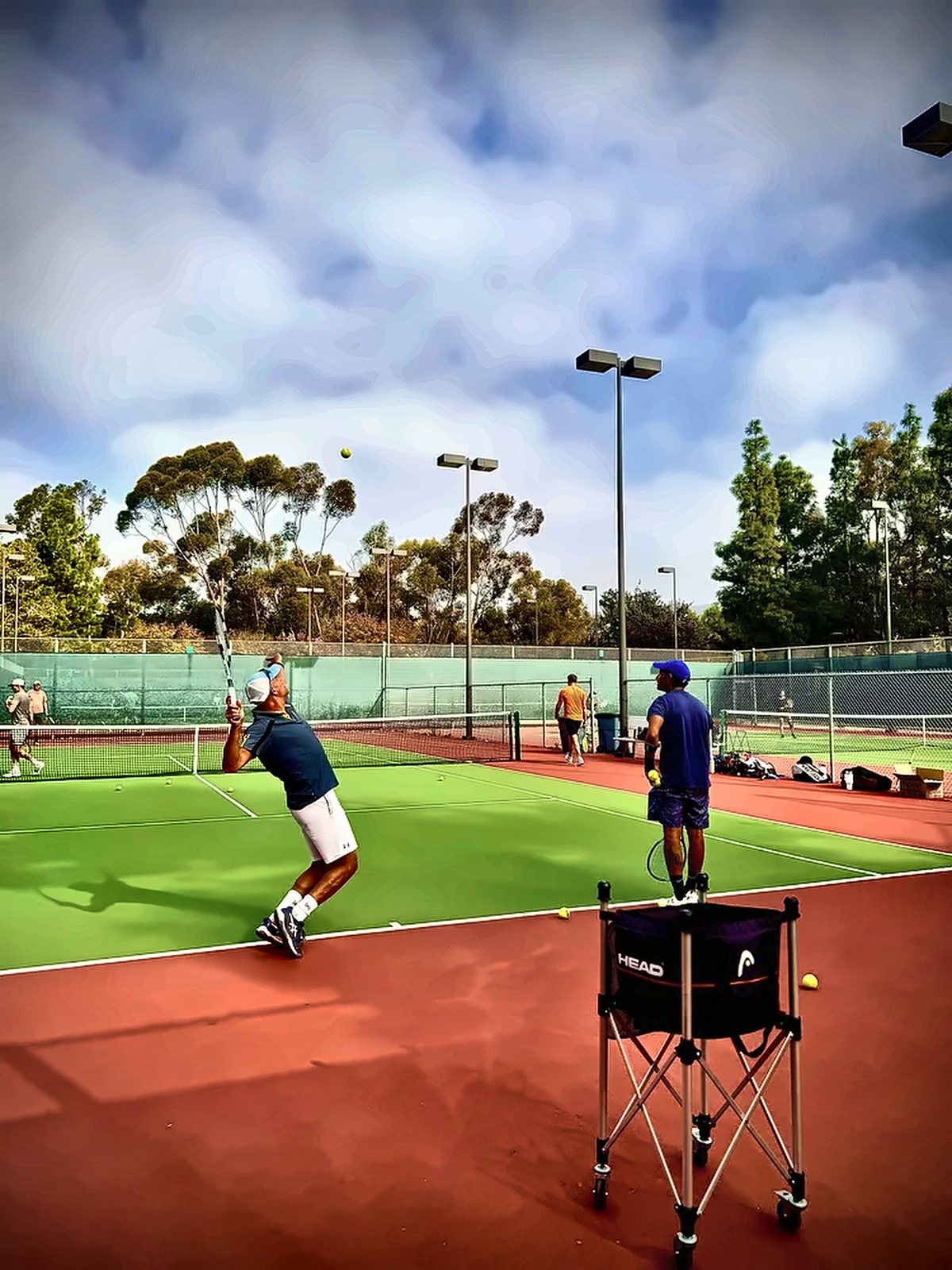 Student serving during a private lesson as Fawz watches